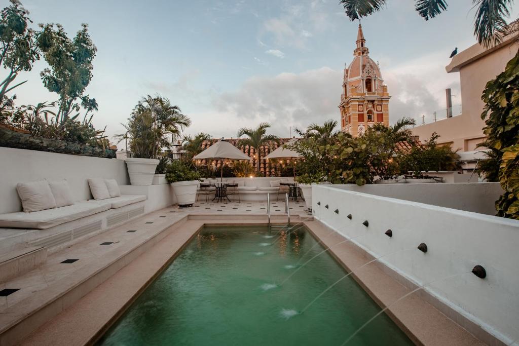 um pátio com uma piscina e uma torre do relógio em Amarla Boutique Hotel Cartagena em Cartagena das Índias
