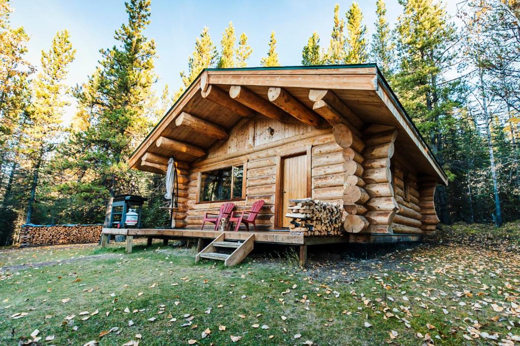 une cabane en rondins avec deux chaises et une table dans l'établissement Rocky Mountain Escape Log Cabin Rentals - Rock Lake, à Rock Lake Lodge Provincial Park
