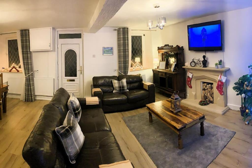 a living room with a leather couch and a fireplace at Cottage nr BikeParkWales/Brecon Beacons/PenYFan in Merthyr Tydfil