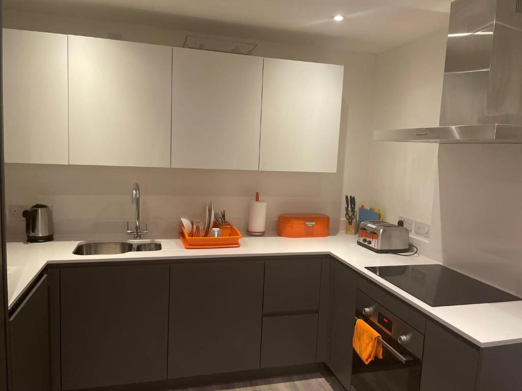 eine Küche mit weißen Schränken und einem orangenen Handtuch in der Unterkunft City centre apartment in Manchester