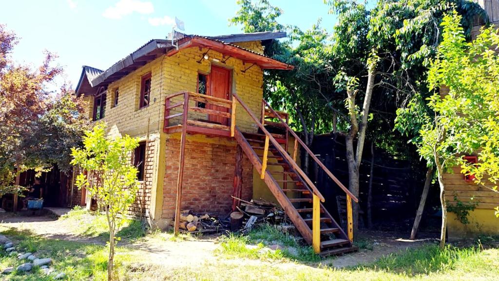 een oud huis met een trap ervoor bij Hostel,Dormis y Camping Costa Bolsón in El Bolsón