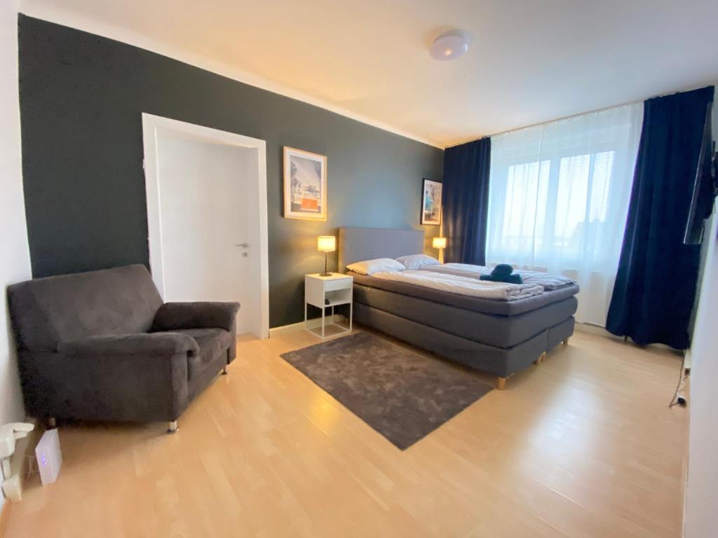 a bedroom with a bed and a couch and a chair at Moderne Wohnung Nähe Hauptbahnhof Linz in Linz