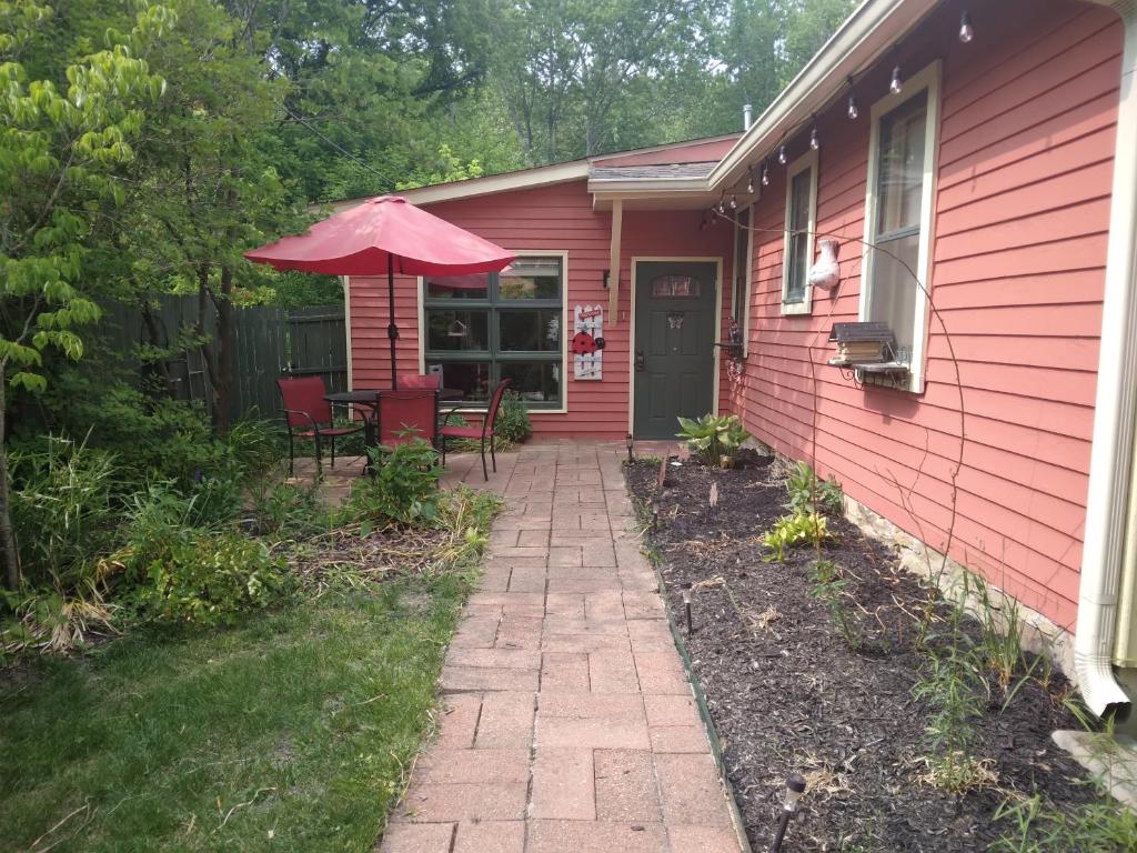 ein rosafarbenes Haus mit einer Terrasse mit einem Sonnenschirm in der Unterkunft Betty Lous Garden in Nashville