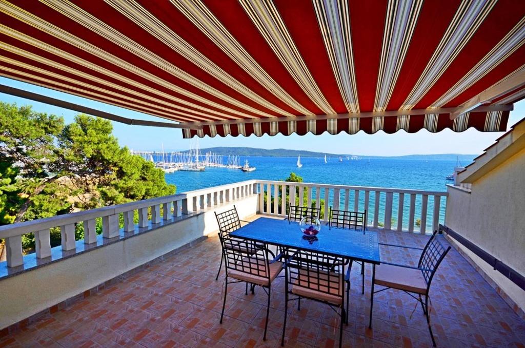 ein Tisch und Stühle auf einem Balkon mit Blick auf das Wasser in der Unterkunft Apartment Luxury Cream in Kaštela
