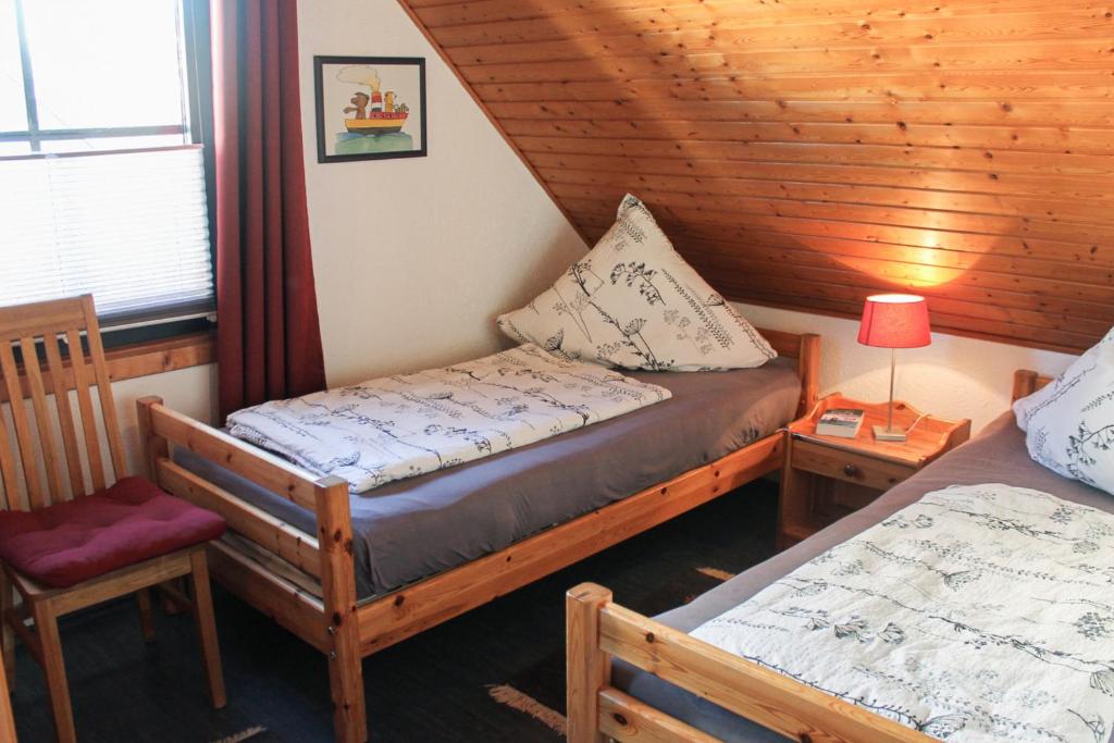 una habitación con 2 camas y una silla en una cabaña en Grömitz, Stiegkamp 3, Whg 2 - große Wohnung mit Balkon, 2 SZ, Nähe Yachthafen und Strand, inkl WLAN en Grömitz