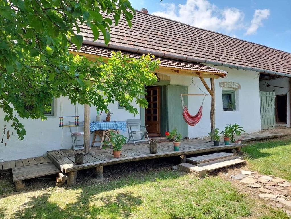 uma pequena casa branca com um deque de madeira em Aracsa Farm és Vendégház Kis Balaton és termál fürdők em Egeraracsa