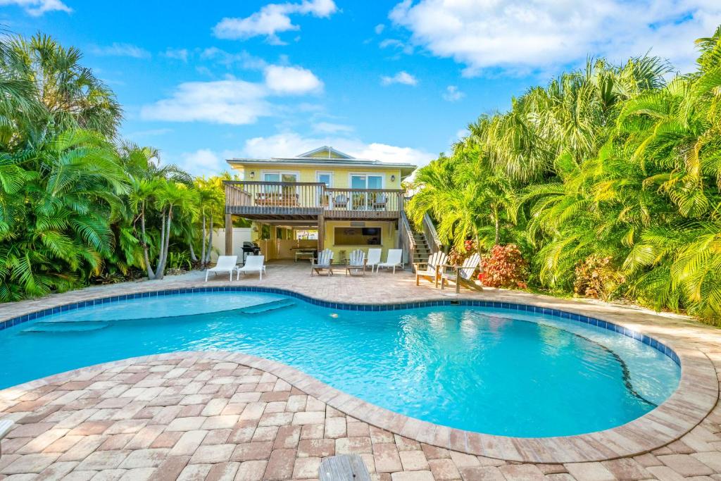- une piscine en face d'une maison avec des palmiers dans l'établissement Cabana Breeze, à Anna Maria