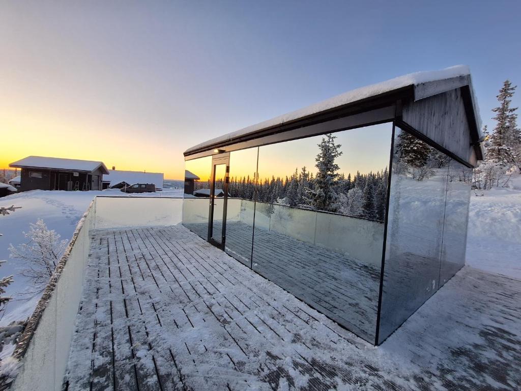 a glass house in the snow with the sunset at SPEGILL in Aurdal