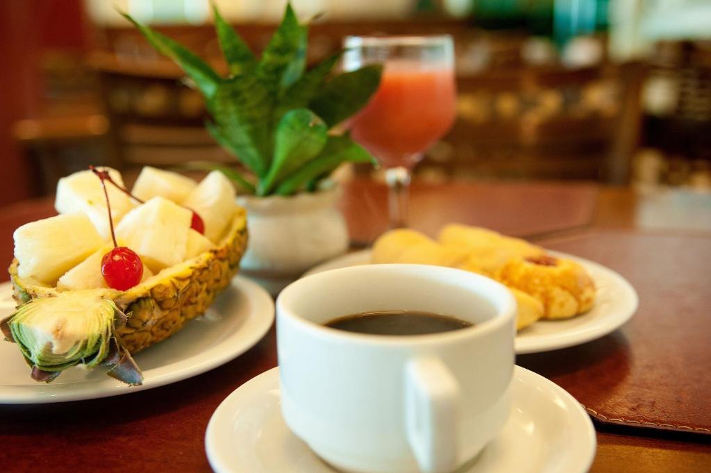 a table with a cup of coffee and a bowl of fruit at Hotel Jangadeiro in Recife