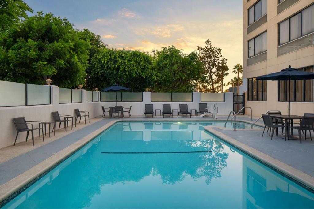 una piscina con sillas y mesas y un edificio en Courtyard by Marriott Cypress Anaheim / Orange County, en Cypress