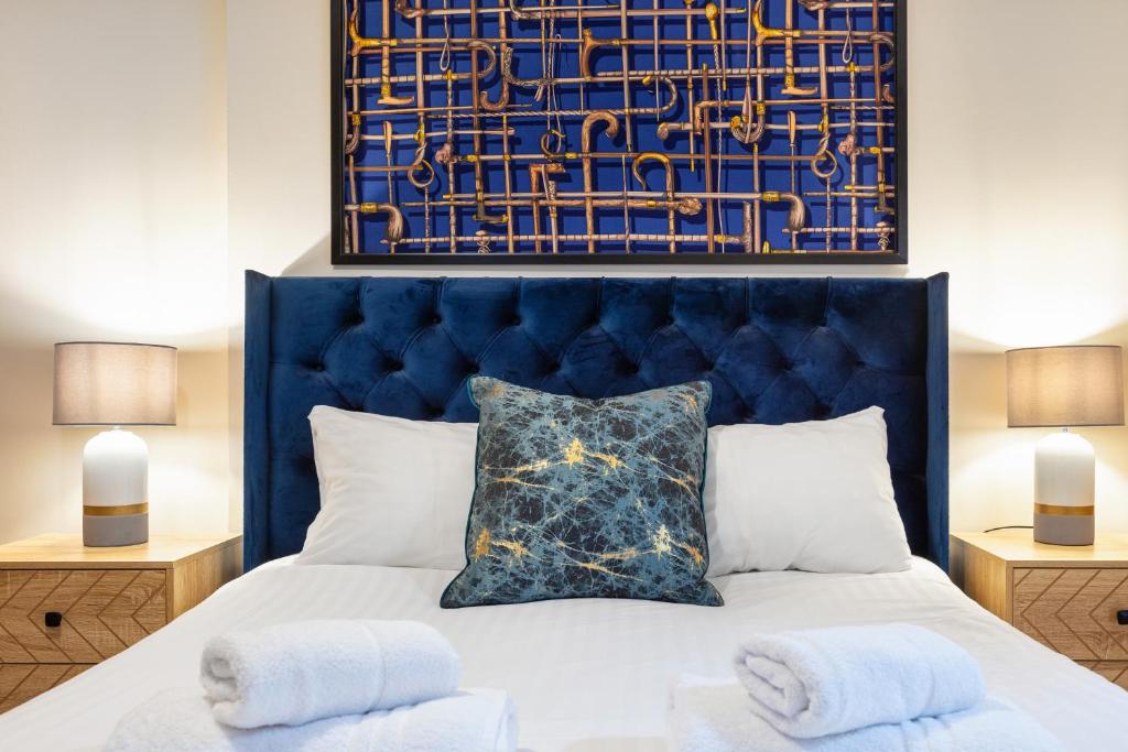 a bedroom with a bed with a blue headboard at Elegant Kensington Apartment with patio in London