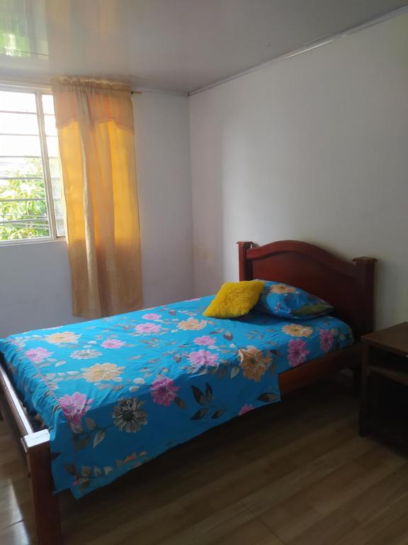 1 dormitorio con 1 cama con edredón azul y ventana en Acogedor apartamento en el salado, en Ibagué
