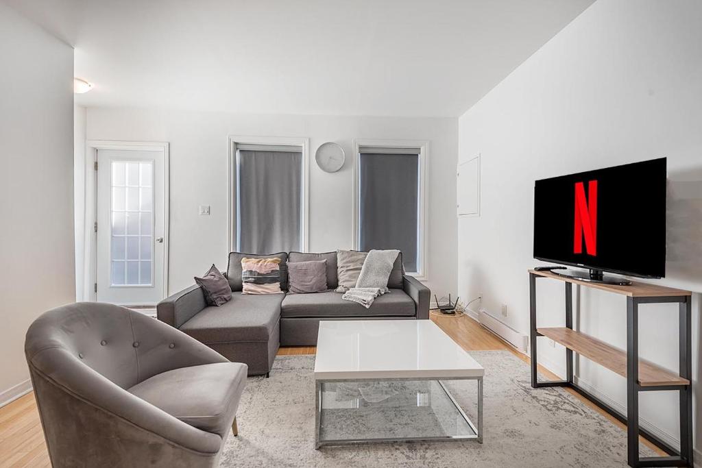 a living room with a couch and a tv at AAA Location Condo & FREE Parking in Montreal