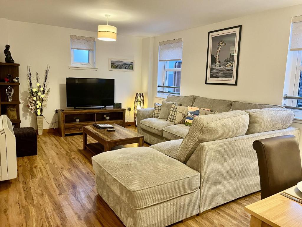 a living room with a couch and a flat screen tv at La Scala Inverness City Apartment in Inverness