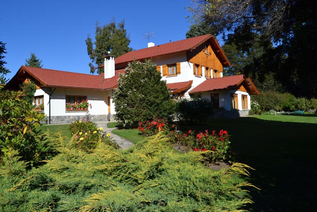 a house with a red roof and some flowers at Hosteria Katy in San Carlos de Bariloche