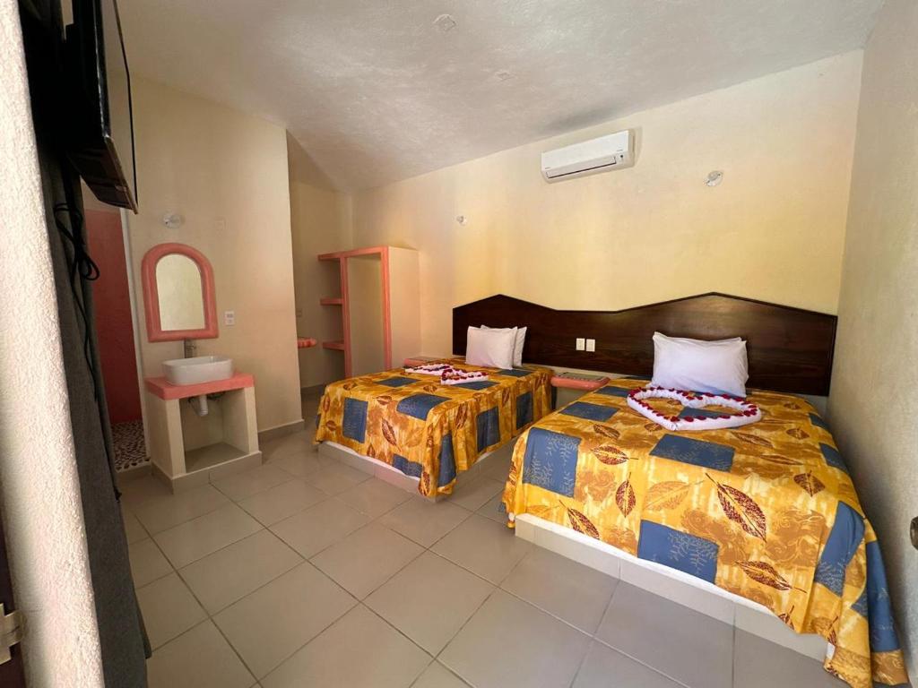 ein Schlafzimmer mit 2 Betten und einem Waschbecken darin in der Unterkunft Hotel Posada Purépechas in Zihuatanejo