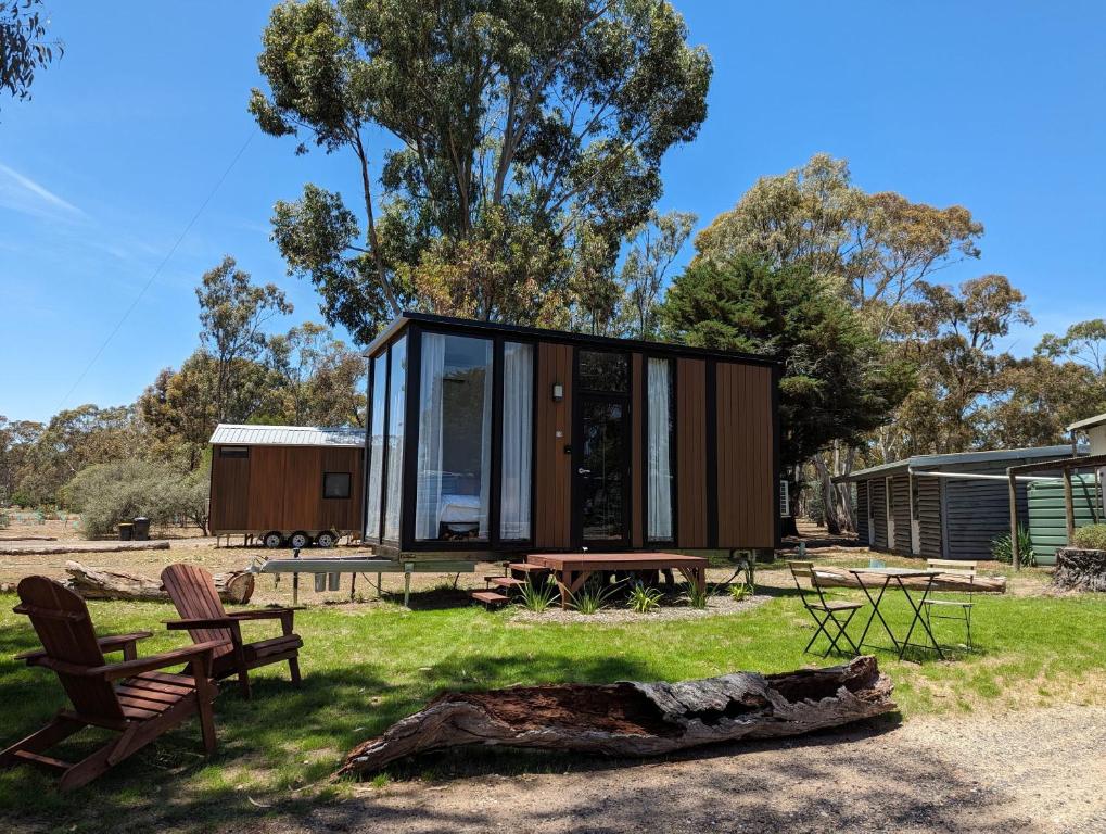 a small house with glass walls and a log at Tiny House 10 at Grampians Edge in Dadswells Bridge