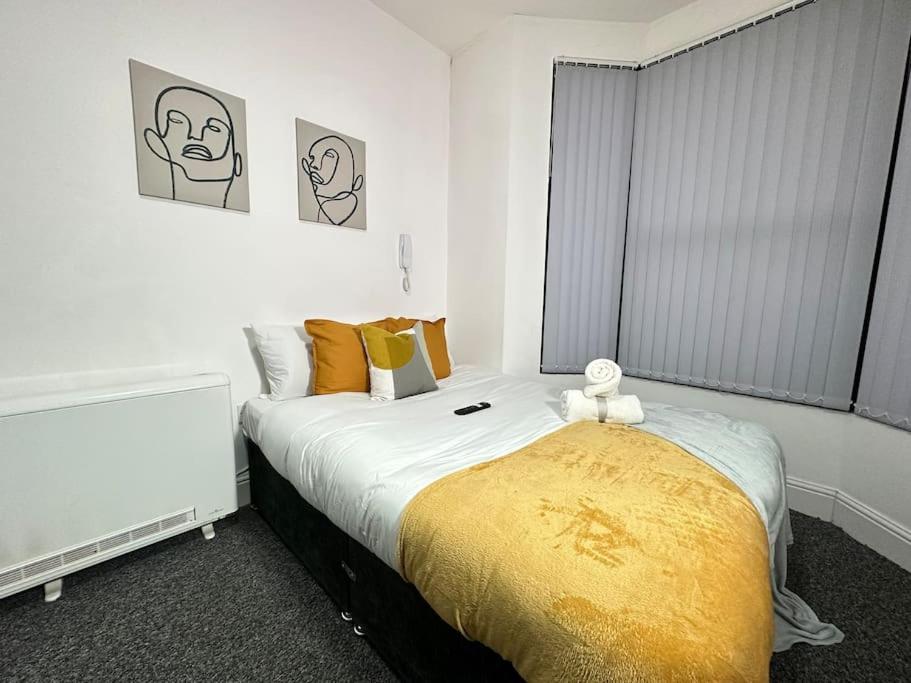 a bedroom with a bed with a yellow blanket at Cosy, fresh studio with Netflix in Kidderminster