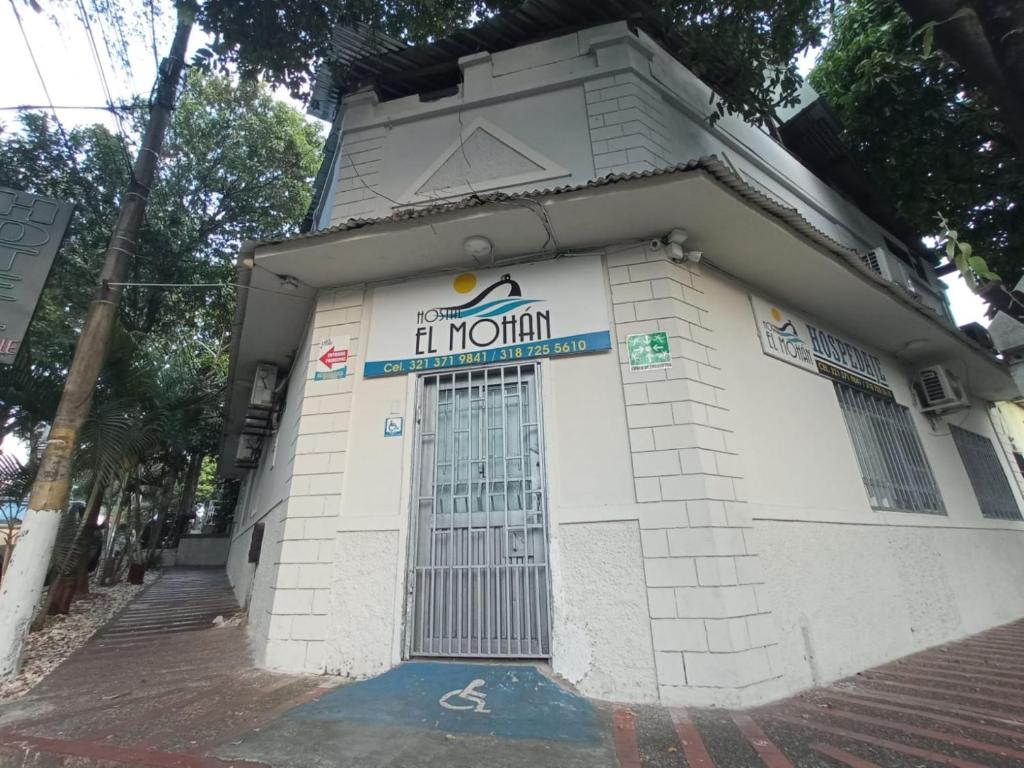 un pequeño edificio blanco con un cartel en él en Hostal El Mohan en Neiva