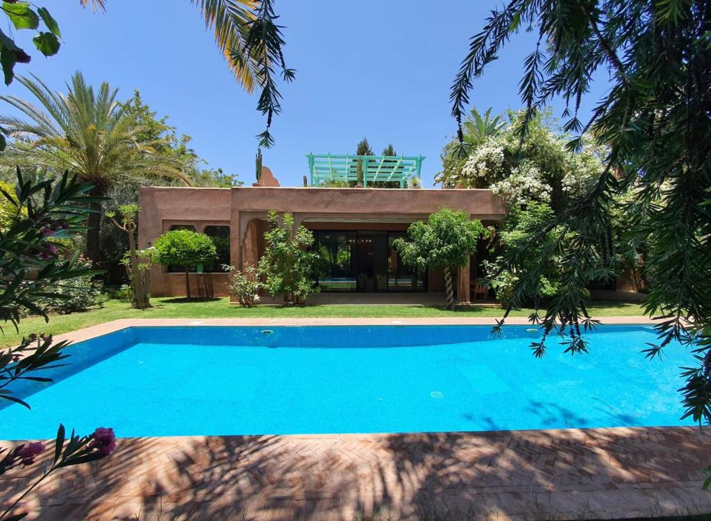 a villa with a swimming pool in front of a house at Bijou de villa Marrakech in Marrakesh