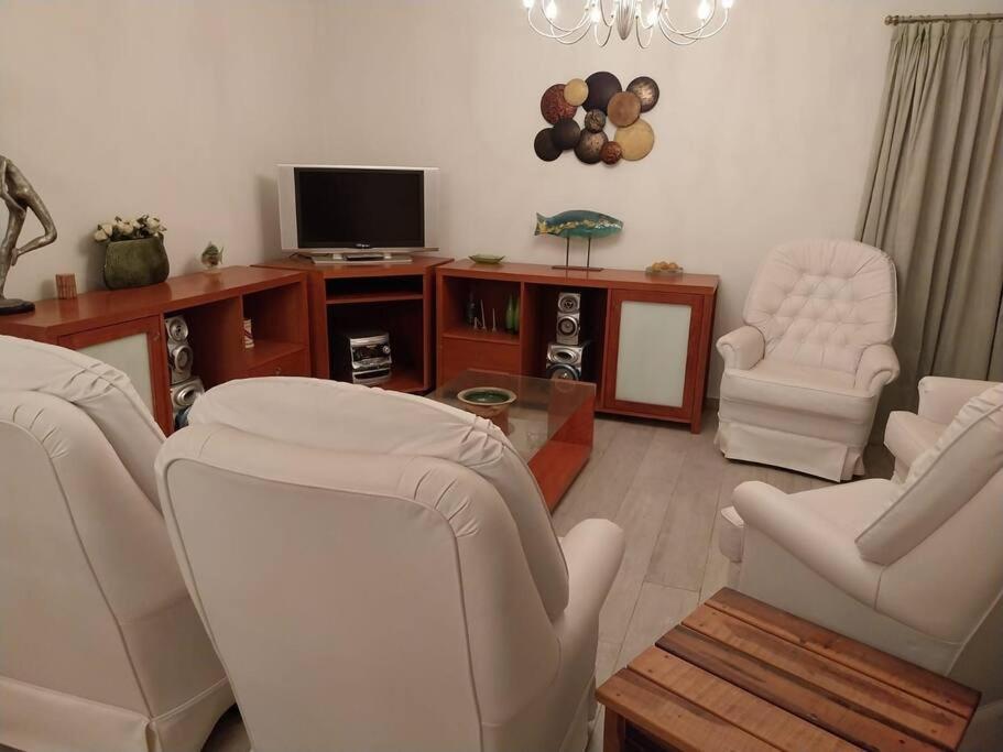 uma sala de estar com duas cadeiras e uma televisão em Apartamento frente al Mar para 7 em Pinamar