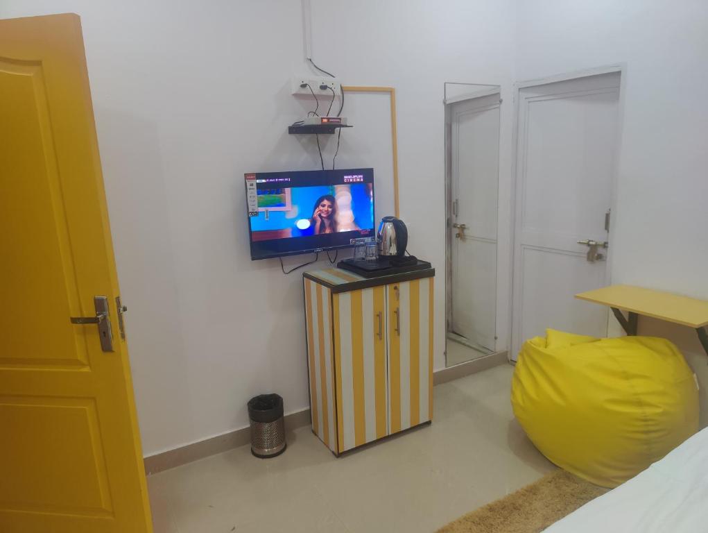 a living room with a tv and a yellow ottoman at Yellow Inn Guest House in Lucknow