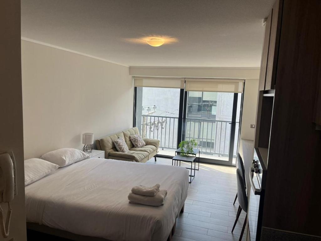 a white bedroom with a bed and a couch at Central Vip Antofagasta in Antofagasta