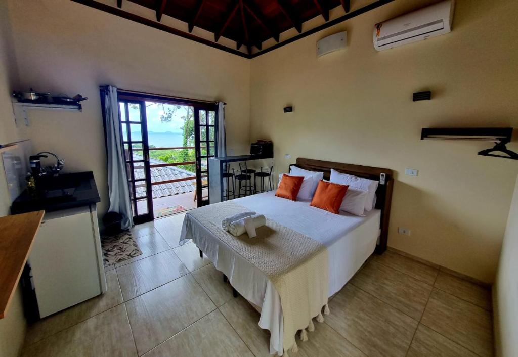 1 dormitorio con 1 cama grande con almohadas de color naranja en Burung Flats Itamambuca - Hospedagem com vista para o mar en Ubatuba