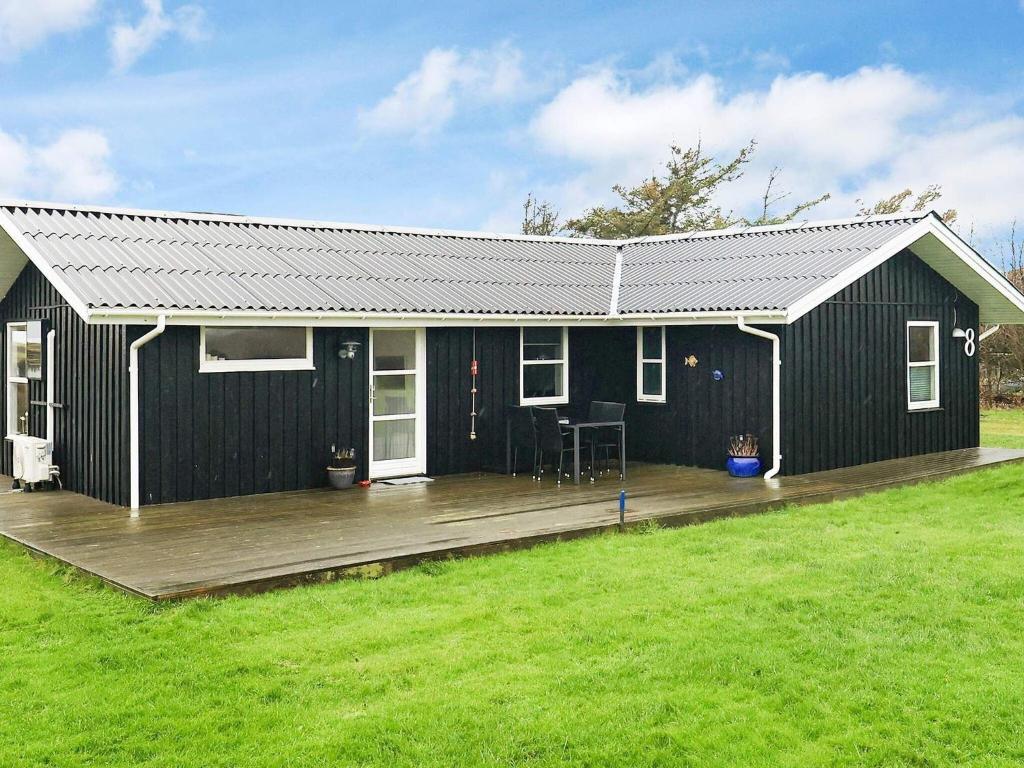ein schwarzes Haus mit einer Holzterrasse im Hof in der Unterkunft Holiday home Løkken IV in Løkken