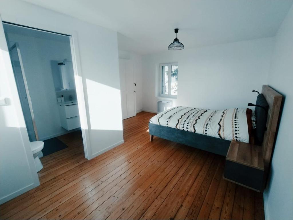 um quarto com uma cama e piso em madeira em C'COZY - grande maison calme et lumineuse em Sablé-sur-Sarthe