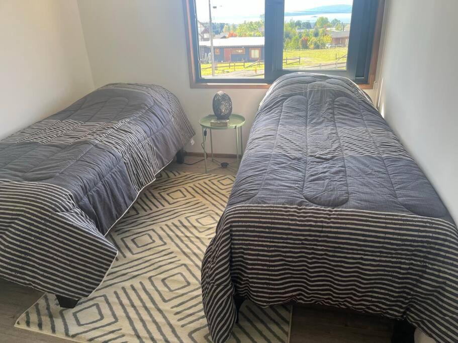 two beds sitting next to each other in a bedroom at Casa nueva en country pucon con piscina y quincho compartido con casa gemela in Pucón