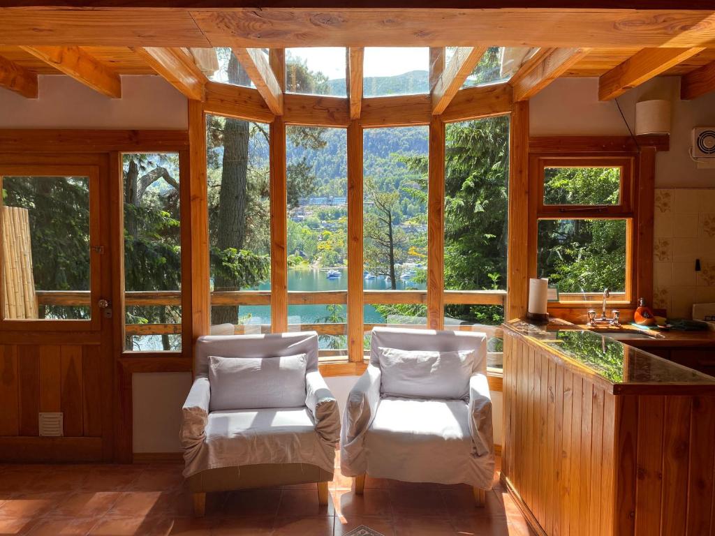 a living room with two chairs and a large window at BOG Le Pommier - Cabañas con vista al lago y piscina climatizada in Villa La Angostura