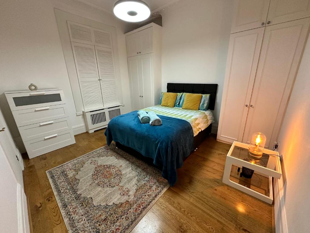 a bedroom with a bed with a blue blanket at Cosy one bedroom flat in London
