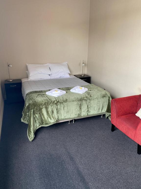 a bedroom with a bed and a red chair at Kaponga Hotel in Kaponga