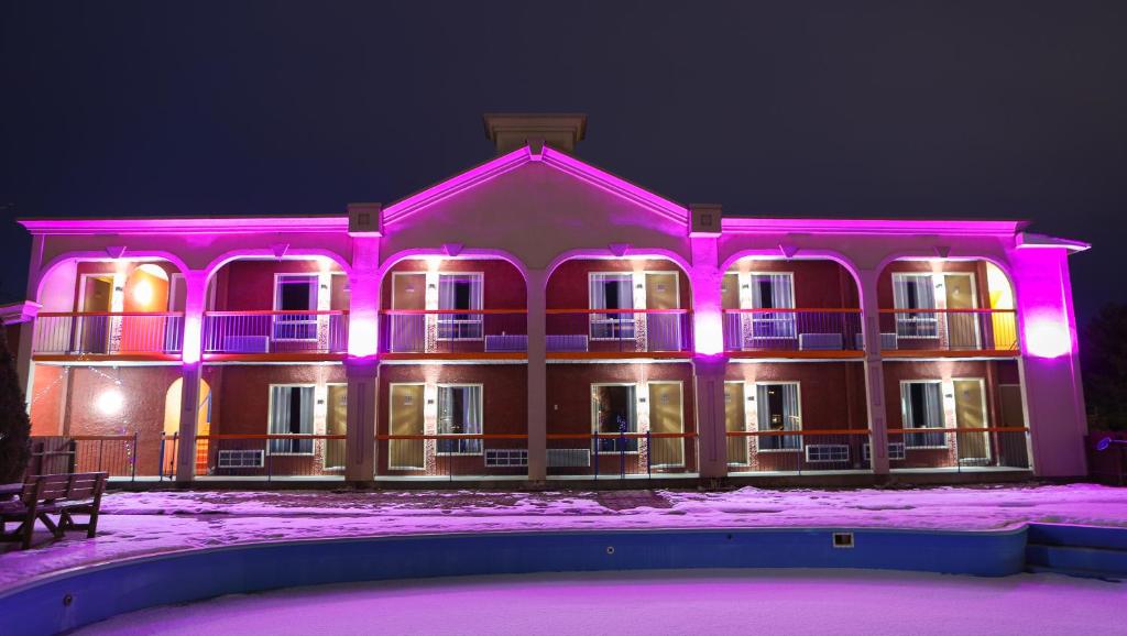 um grande edifício com luzes cor-de-rosa em Motel Classique em Joliette