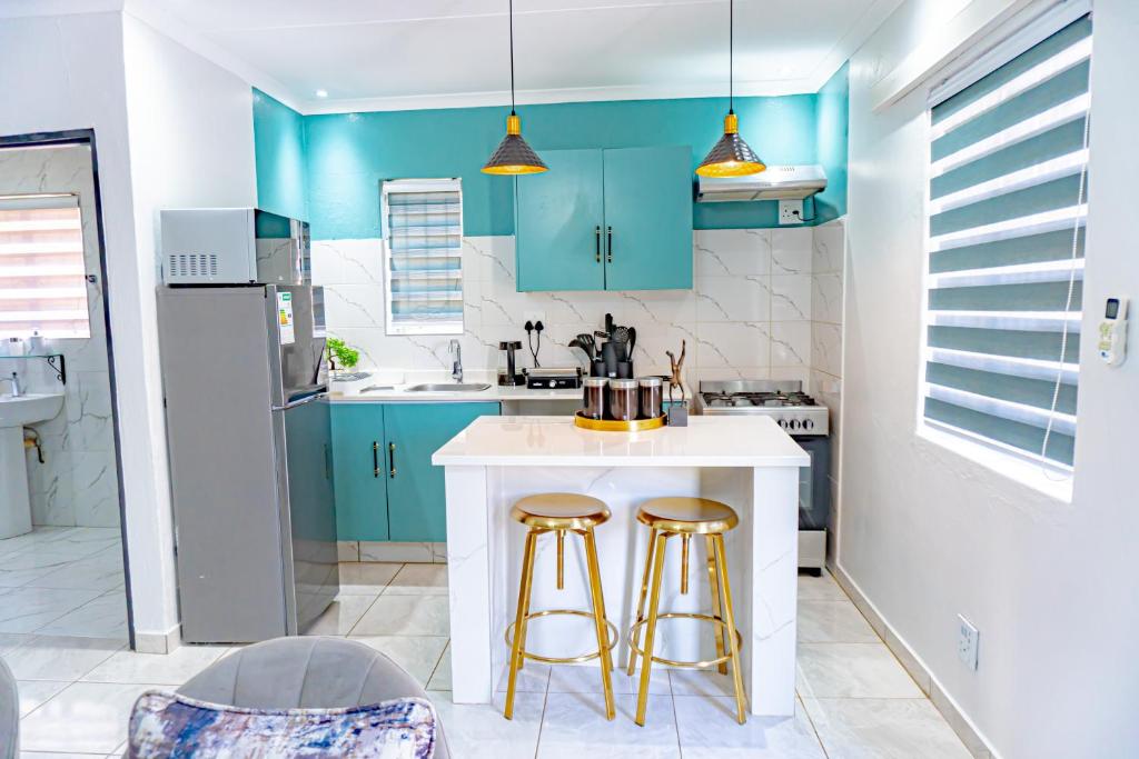 a kitchen with blue cabinets and two bar stools at Homes of Ace Gold in Pretoria