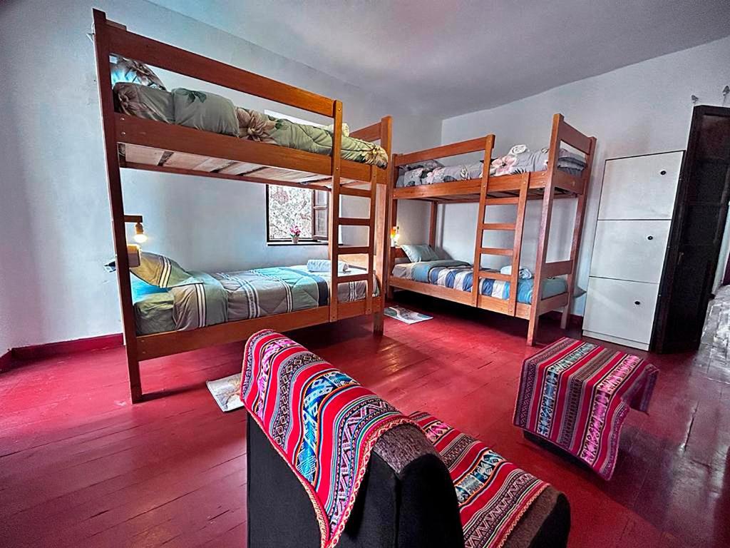 クスコにあるMORENAS BACKPACKERsの二段ベッド3台とソファが備わる客室です。