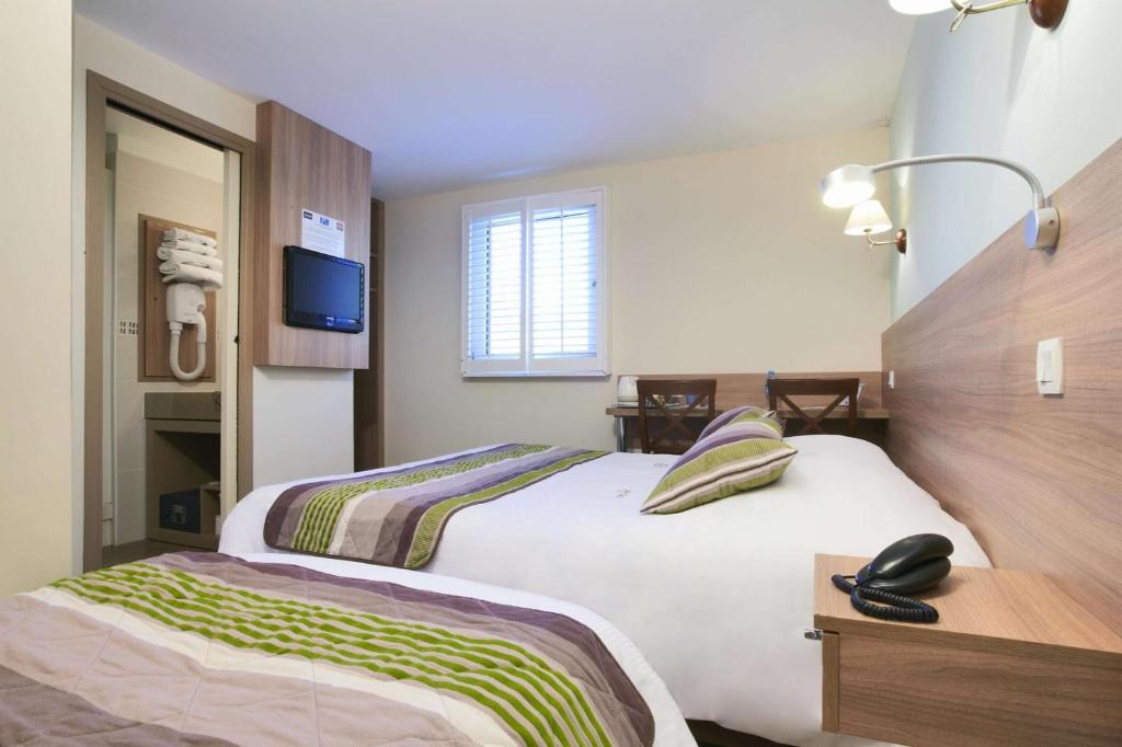 ein Hotelzimmer mit 2 Betten und einem TV in der Unterkunft BRIT HOTEL Le 940 Le Touquet-Etaples in Étaples
