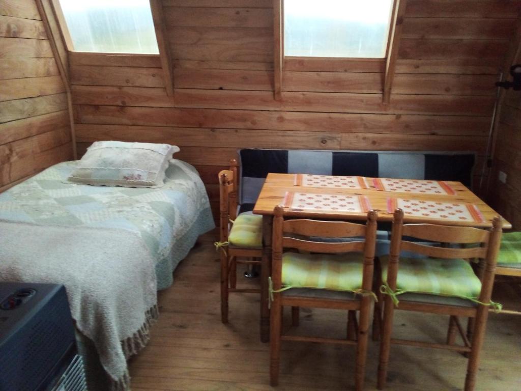 a room with a bed and a table and chairs at Linda cabaña en Puyehue con vista al volcán in Ñilque