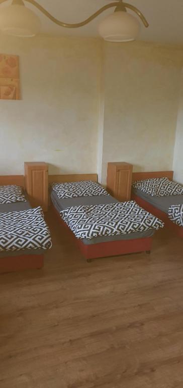 3 camas num quarto com pisos em madeira em Mieszkanie 6 osobowe em Tomaszów Mazowiecki