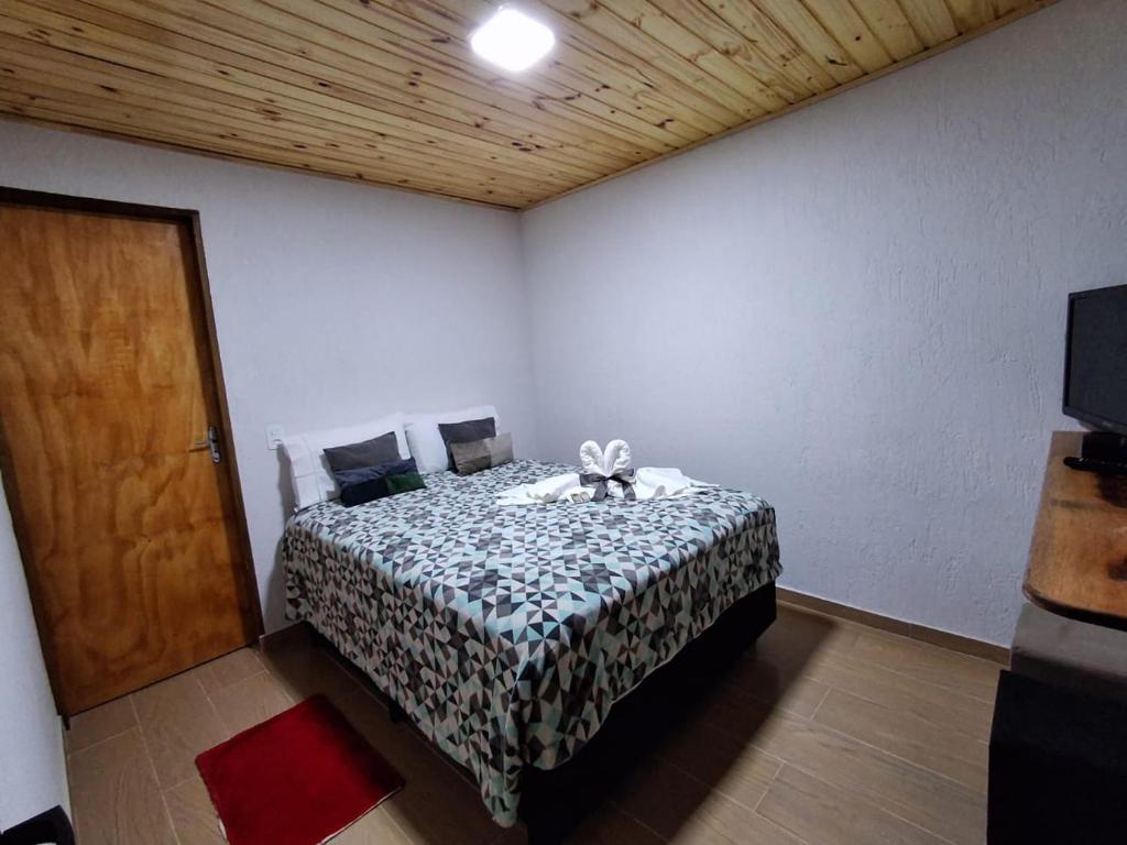 a bedroom with a bed in a room with a door at Pousada Lofts e Suítes Campos in Campos do Jordão