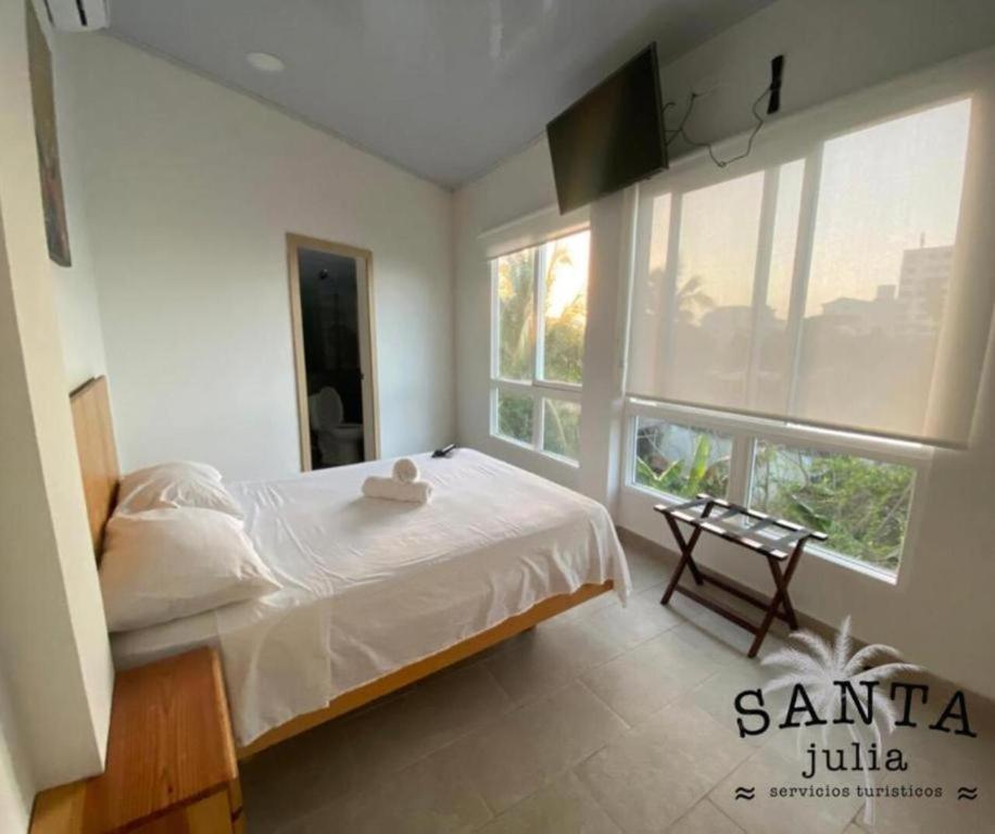 a bedroom with a bed and two large windows at Santa Julia Travel in San Andrés