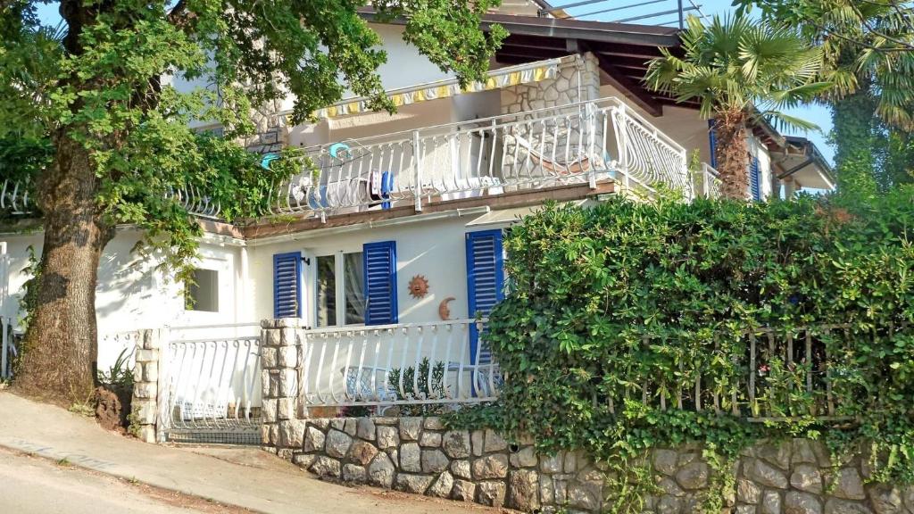 uma casa branca com persianas azuis e uma parede de pedra em Apartments with a parking space Njivice, Krk - 21767 em Njivice