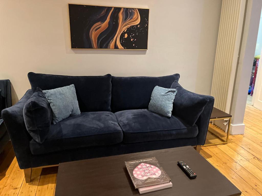 um sofá azul numa sala de estar com uma mesa em Extra Large, Modern Family Home in Finchley London Close to Station and Central London em Finchley