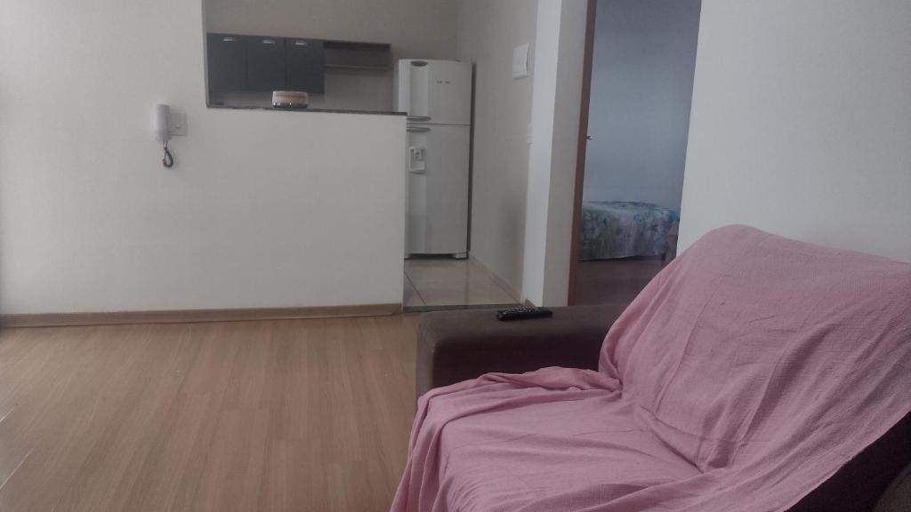ein Wohnzimmer mit einem Bett und einem Kühlschrank in der Unterkunft Apartamento Super Aconchegante em Ambiente Familiar in Contagem
