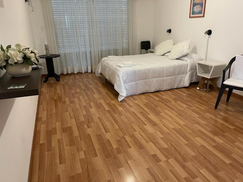 Un dormitorio con una cama y suelo de madera. en Ruffus´s Apple Rosario, en Rosario