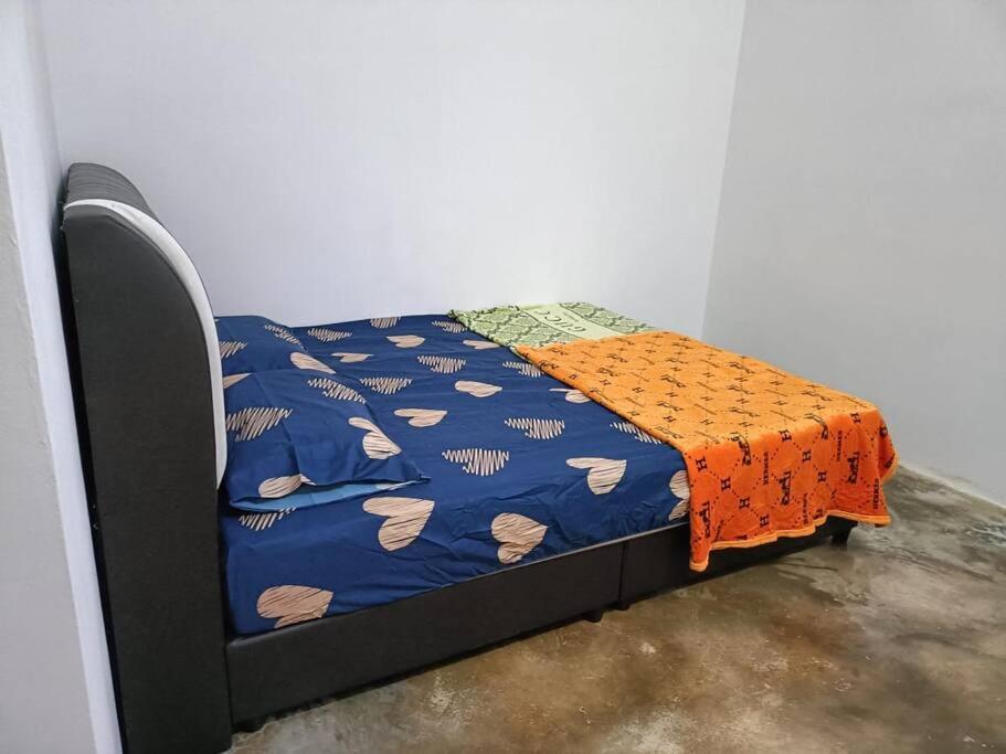 uma pequena cama com um cobertor laranja em Bukit Bayan TOWNHOUSE em Sungai Petani