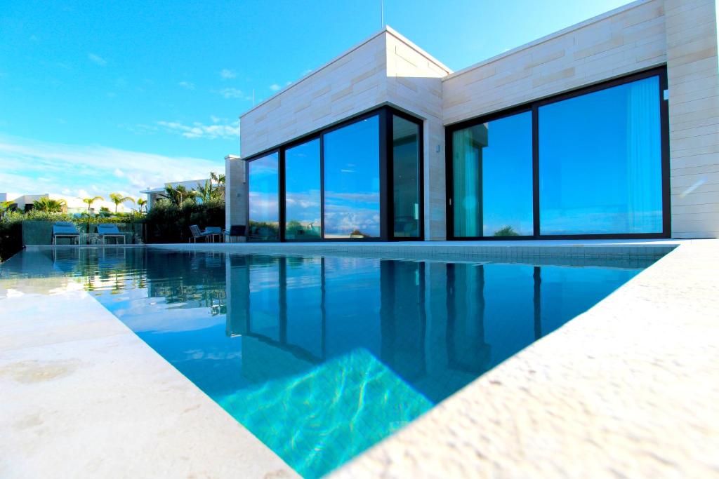 une maison avec une piscine et des fenêtres en verre dans l'établissement Deluxe Villa Jante Infinity Pool, à Durrës
