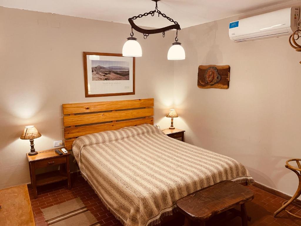 1 dormitorio con 1 cama, 2 mesas y 2 lámparas en Departamento en el centro Tafi del Valle en Tafí del Valle
