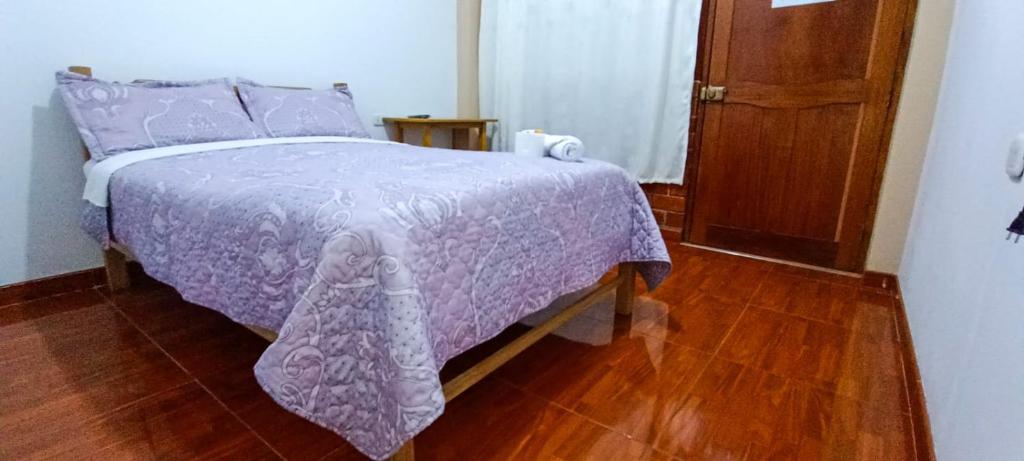 - une chambre avec un lit violet et du parquet dans l'établissement Hospedaje Fortaleza, à Oxapampa